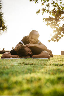 Müder Mann mit Tochter auf dem Rücken nach dem Sport im Park bei Sonnenuntergang - MASF36584