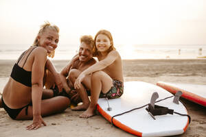 Porträt einer glücklichen Familie mit Tretbooten am Strand bei Sonnenuntergang - MASF36598