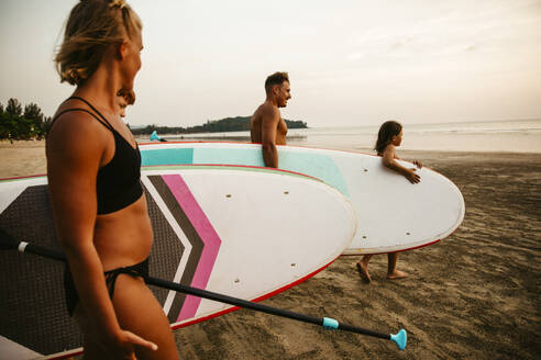 Familie mit Paddleboards am Strand bei Sonnenuntergang im Urlaub - MASF36600