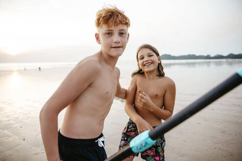 Portrait eines Geschwisterpaares, das bei Sonnenuntergang seine Freizeit am Strand verbringt - MASF36606