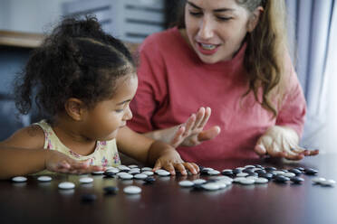 Mutter spielt Go-Spiel mit Tochter auf Tisch zu Hause - IKF00042