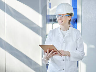 Woman wearing lab coat with tablet PC in laboratory - CVF02359