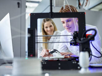 Engineer with colleague operating 3D printing machine in laboratory - CVF02365