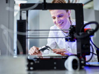 Happy engineer operating 3D printing machine in laboratory - CVF02366