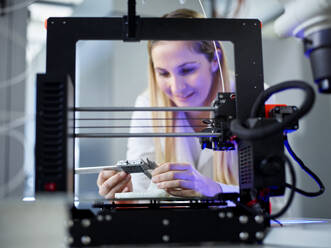 Smiling engineer with vernier calliper operating 3D printing machine - CVF02369