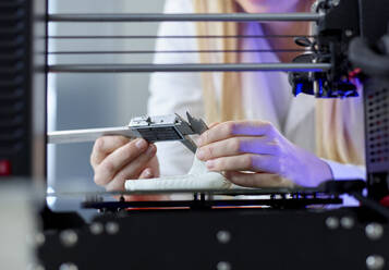 Hands of woman using vernier calliper at 3D printing machine in laboratory - CVF02370