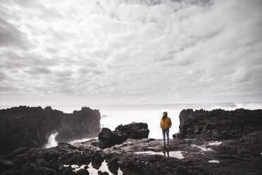 Woman standing on rock in front of sea - PCLF00345