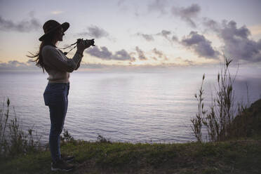 Junge Frau fotografiert durch die Kamera vor dem Meer - PCLF00347