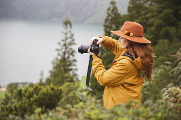 Rothaarige Frau mit Hut fotografiert durch Kamera im Wald - PCLF00354