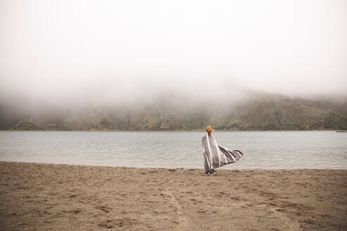 Woman wearing poncho standing in front of lake - PCLF00364