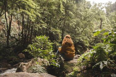 Young redhead woman sitting on rock in forest - PCLF00371