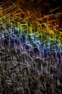Long exposure of spray of water covered in rainbow colored light - NDF01552