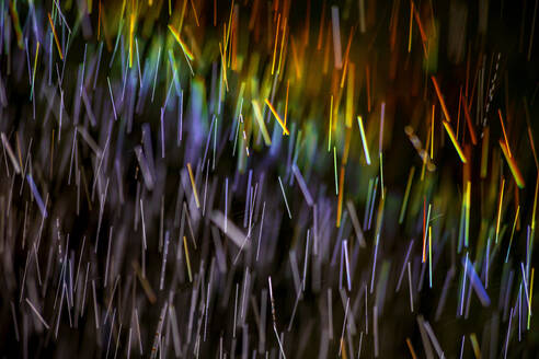 Long exposure of spray of water covered in rainbow colored light - NDF01553