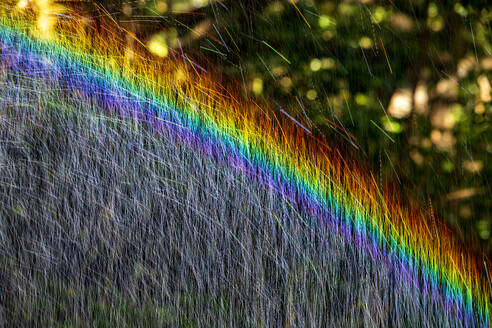 Long exposure of spray of water covered in rainbow colored light - NDF01554