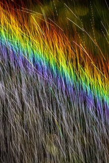 Long exposure of spray of water covered in rainbow colored light - NDF01555
