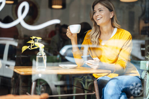 Glückliche Frau mit Mobiltelefon und Kaffeetasse am Tisch im Café - JOSEF18253