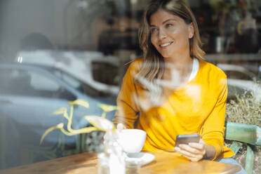 Glückliche Frau trinkt Kaffee in einem Café, gesehen durch Glas - JOSEF18255