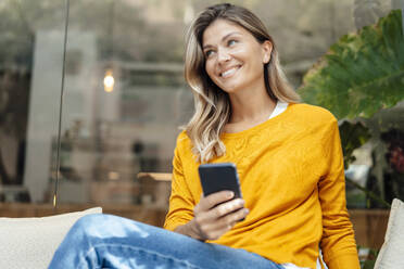 Glückliche Frau mit Smartphone in einem Café sitzend - JOSEF18265