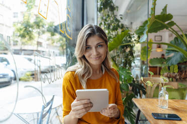 Lächelnde Frau mit Tablet-PC im Cafe sitzend - JOSEF18288