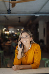 Happy woman taking on mobile phone in cafe - JOSEF18321