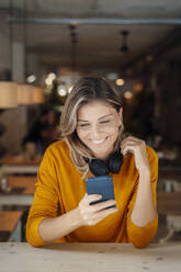 Glückliche Frau, die mit ihrem Smartphone in einem Café im Internet surft - JOSEF18328