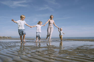 Happy mother enjoying with children at beach - NDEF00485