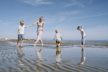 Happy mother playing with children at beach - NDEF00487