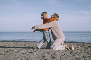 Glückliche Mutter, die ihre Tochter am Strand umarmt - NDEF00491