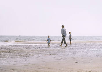 Verspielte Mutter genießt mit Kindern am Strand - NDEF00495