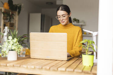 Lächelnder junger Freiberufler, der zu Hause am Laptop arbeitet - JCCMF10109