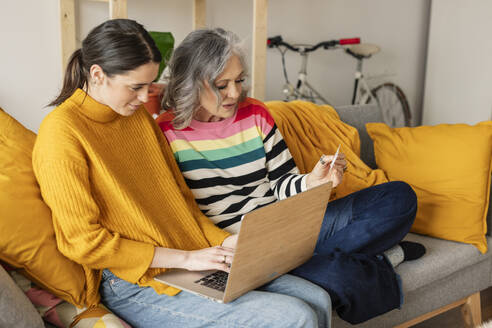 Tochter und Mutter beim Online-Shopping mit Kreditkarte auf dem Laptop - JCCMF10141