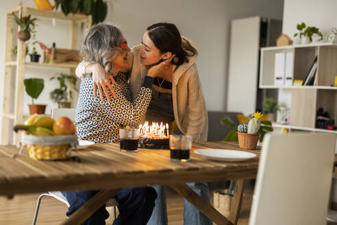 Happy mother embracing daughter and celebrating birthday at home - JCCMF10167