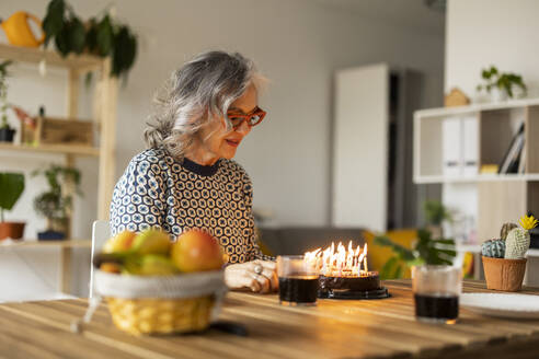 Lächelnde reife Frau feiert Geburtstag zu Hause - JCCMF10168