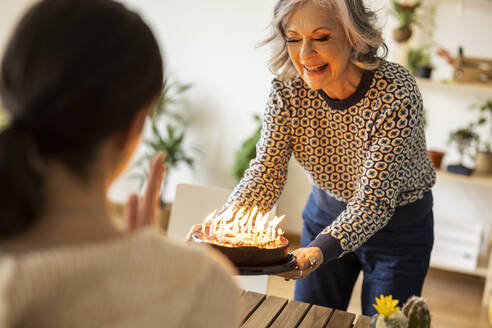 Lächelnde reife Frau, die den Geburtstag ihrer Tochter zu Hause feiert - JCCMF10172