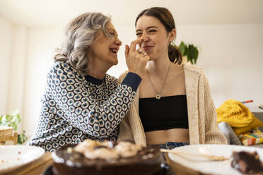 Glückliche Mutter trägt zu Hause Schokolade auf die Nase ihrer Tochter auf - JCCMF10180