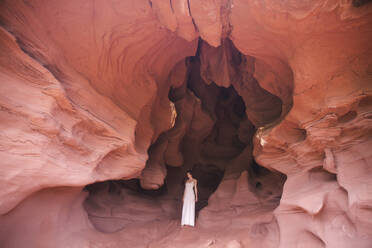 Junge Frau in weißem Kleid steht in roter Höhle - PCLF00394