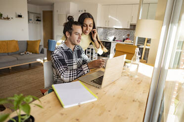 Couple having discussion over laptop at home office - JCCMF10219