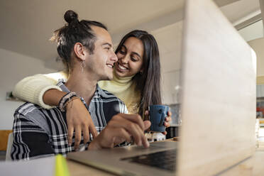 Happy woman with arm around boyfriend at home office - JCCMF10223