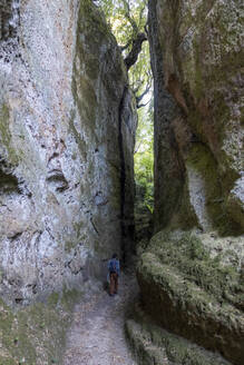 Mann, der auf einer schmalen Straße inmitten von Felsen geht, Toskana, Italien - MAMF02766