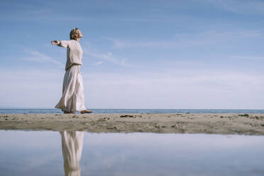 Woman walking with arms outstretched at beach - NDEF00500