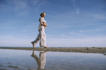Reflexion einer Frau, die am Strand spazieren geht - NDEF00503