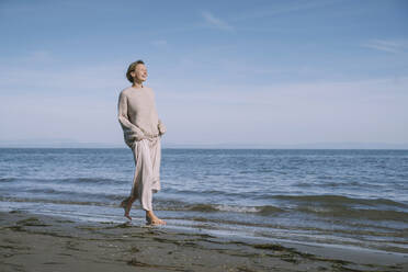 Smiling woman walking on shore at beach - NDEF00505