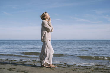 Woman walking on shore at beach in front of sky - NDEF00507