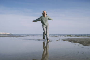 Happy woman running on shore at beach - NDEF00509