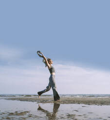 Reflection of woman enjoying at beach in front of sky - NDEF00516