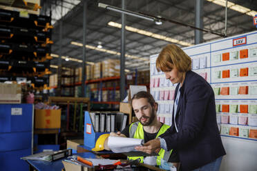 Manager showing checklist to colleague at warehouse - IKF00047