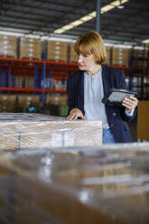 Manager with tablet PC supervising stock in warehouse - IKF00075
