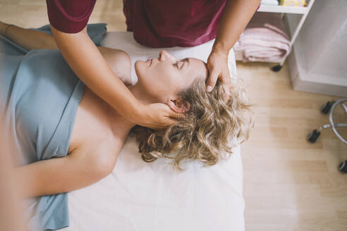 Therapeutin bei der Nackenmassage einer Kundin im Friseursalon - NDEF00521