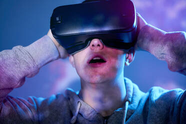 Young man wearing VR glasses in front of projection screen - ABIF01950