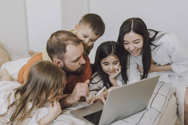 Happy family using laptop in bedroom at home - VBUF00285